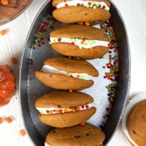 **Whoopie Pies alla Zucca con Ripieno al Mascarpone d'Acero** 7 Foto dall'alto di whoopie pies alla zucca disposti su un vassoio ovale in acciaio.