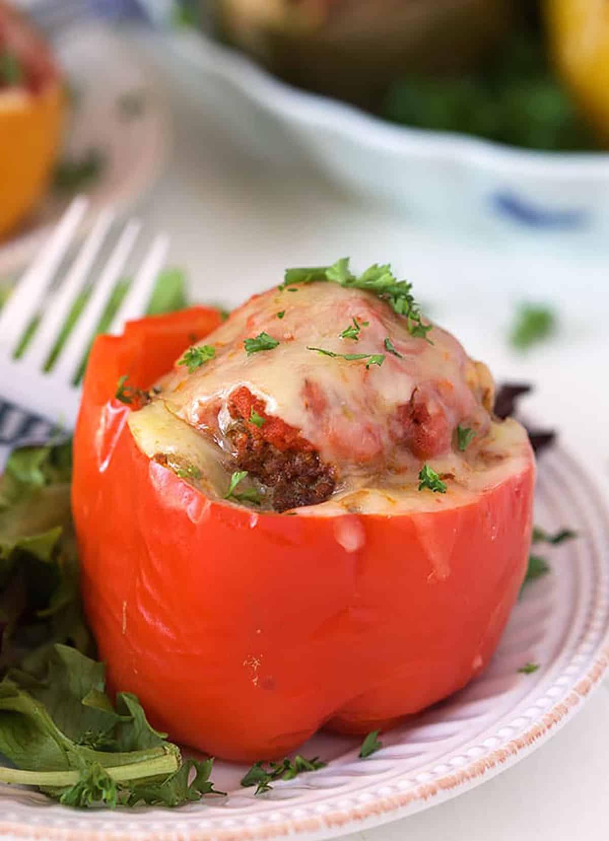 Ricetta Peperoni Ripieni Instant Pot 7 Peperone rosso ripieno su un piatto.