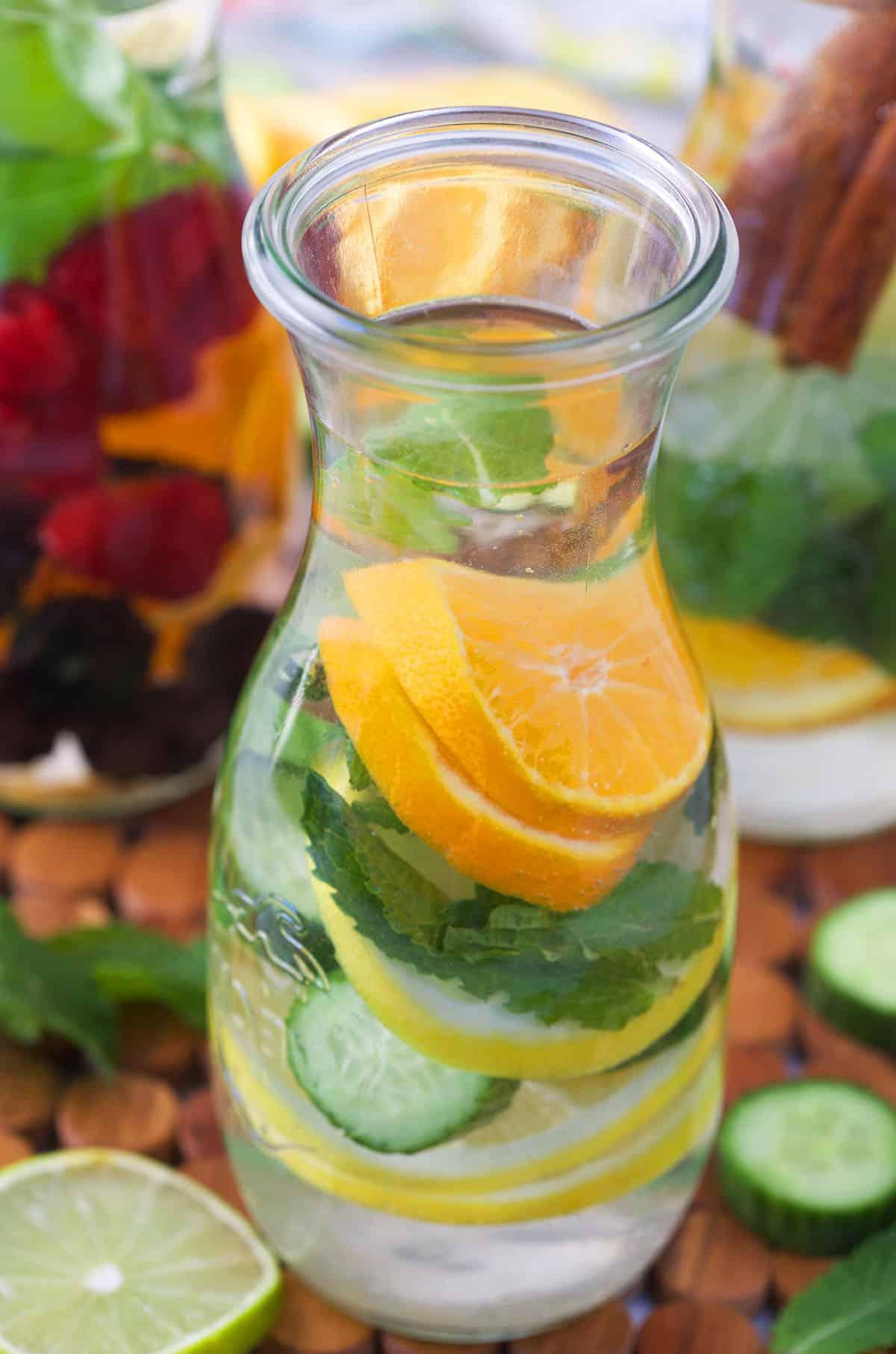 Acqua Infusa di Frutta 7 Acqua aromatizzata alla frutta in una bottiglia di vetro con agrumi, erbe e cetriolo.