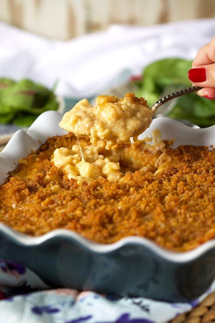 Merluzzo al Forno al Limone e Verdure 7 Mac and Cheese al cavolfiore al forno in una pirofila blu con una crosta croccante e un cucchiaio che lo tiene sopra.