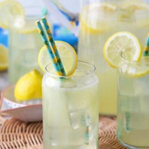 Ricetta della Limonata Fatta in Casa 8 3 bicchieri di limonata su una tovaglietta di vimini.