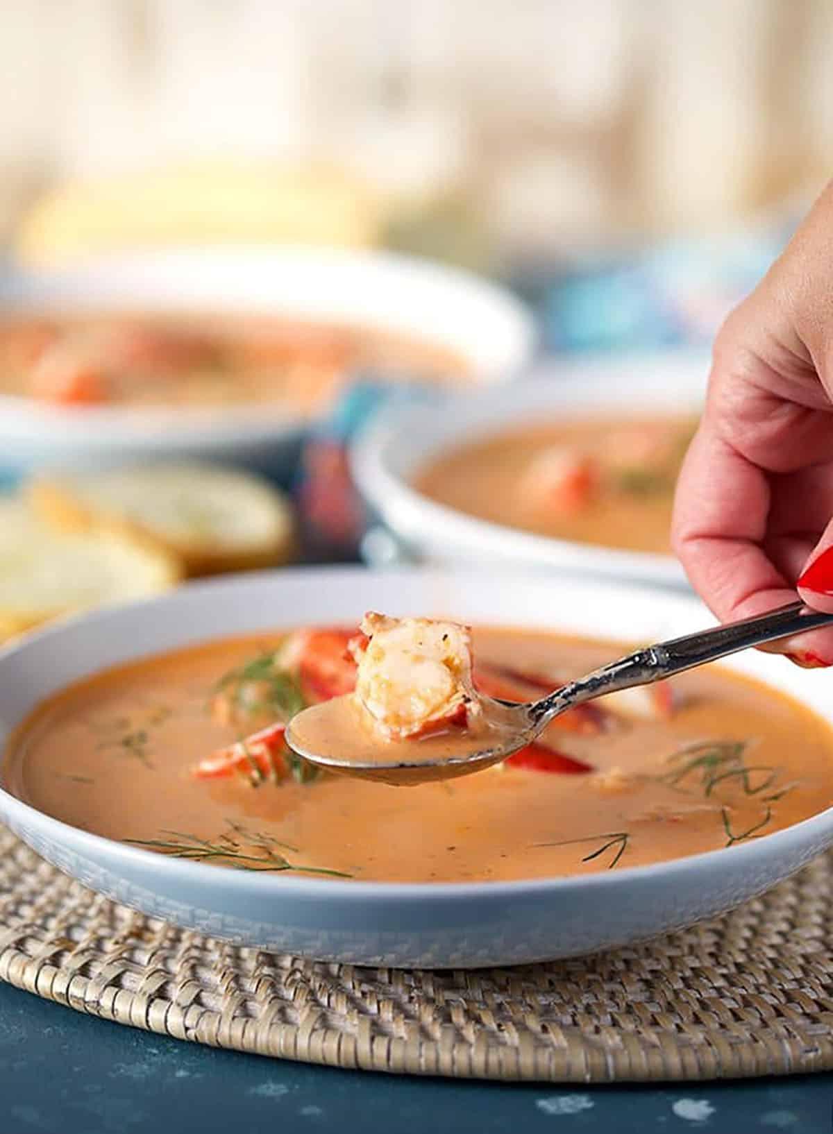 Bisque di Aragosta Facile 8 Bisque di Astice in una ciotola bianca poco profonda con un cucchiaio di astice sopra.