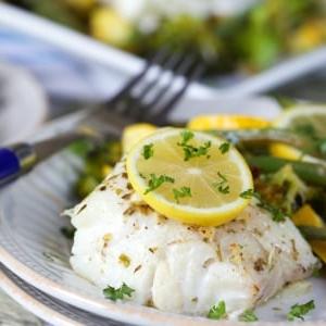 Merluzzo al Forno al Limone e Verdure 9 Filetto di merluzzo al forno al limone su un piatto bianco con verdure.