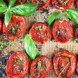**Pomodori Arrostiti al Forno Facili** 9 Primo piano di pomodori arrostiti al forno con basilico ed erbe aromatiche, pronti per essere serviti.