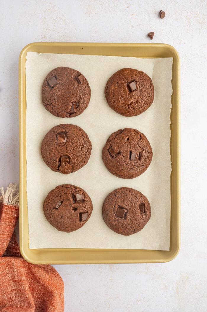 **Biscotti Doppio Cioccolato** 9 Biscotti al doppio cioccolato su teglia rivestita di carta forno, vista dall'alto