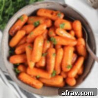 Air fried roasted baby carrots in a gray serving bowl with a serving spoon.