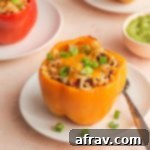Air fryer stuffed peppers arranged on white plates and garnished with green onions.