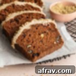 Slices of carrot cake loaf topped with cashew cream frosting and arranged on a sheet of parchment paper.