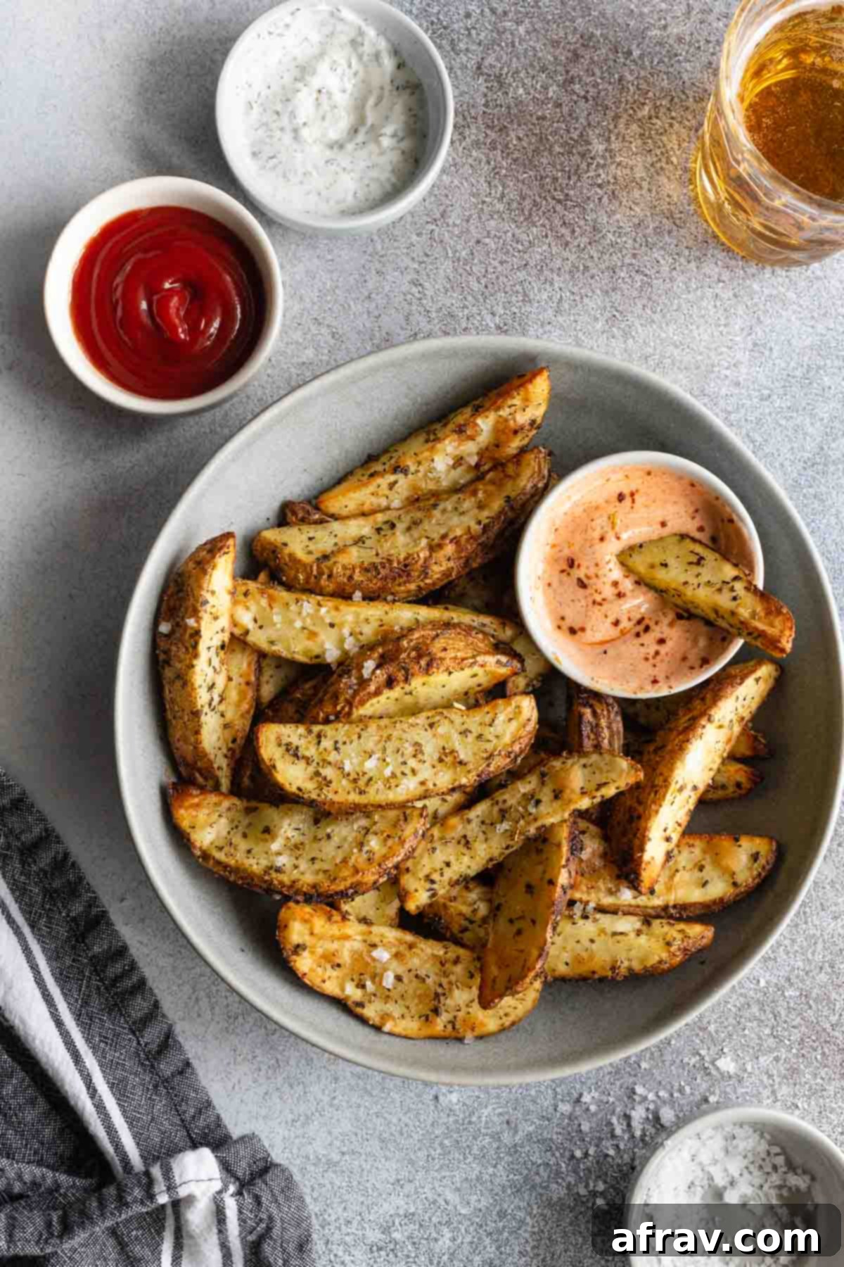 Overhead view of wedge fries in a grey bowl with a bowl of spicy dip.