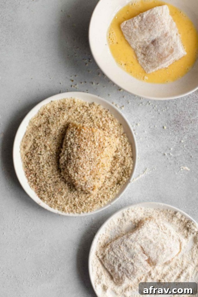 Process of breading cod with pieces of cod being rolled in flour, dipped in egg and coated in panko crumbs.