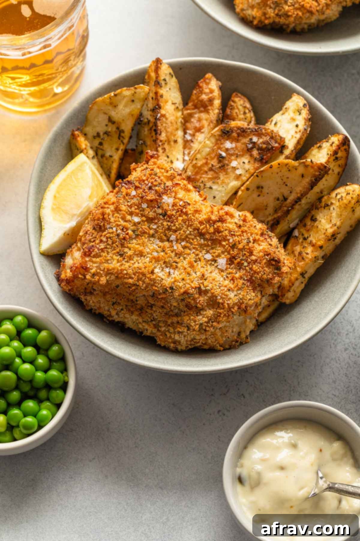 Overhead view of air fried fish and wedge fries in a grey bowl.