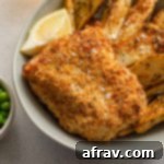 Up close view of a piece of air fried cod in a bowl with fries.