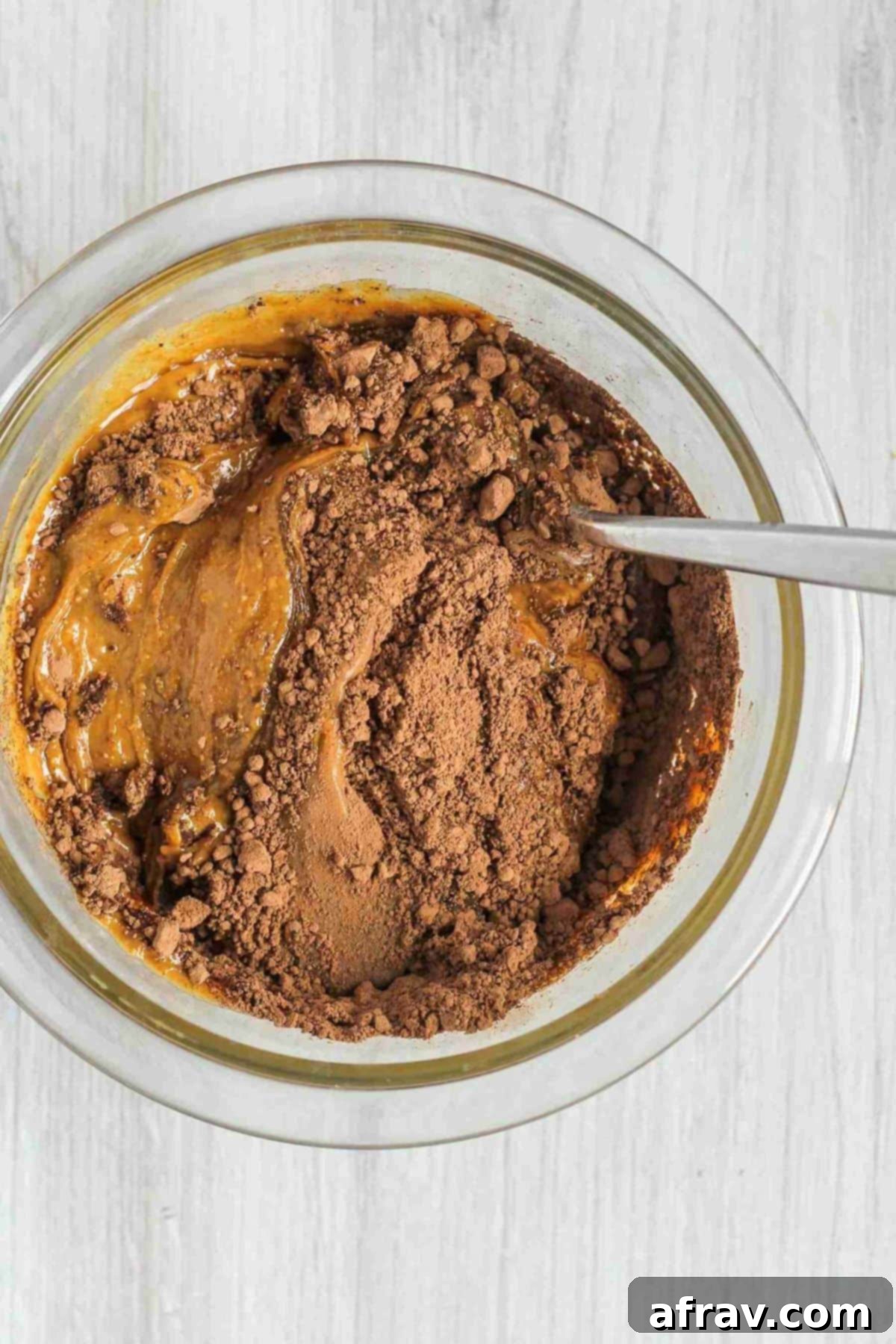 Chocolate Coconut Peanut Butter Balls 3 Peanut butter, honey, and cacao being mixed together in a glass mixing bowl.
