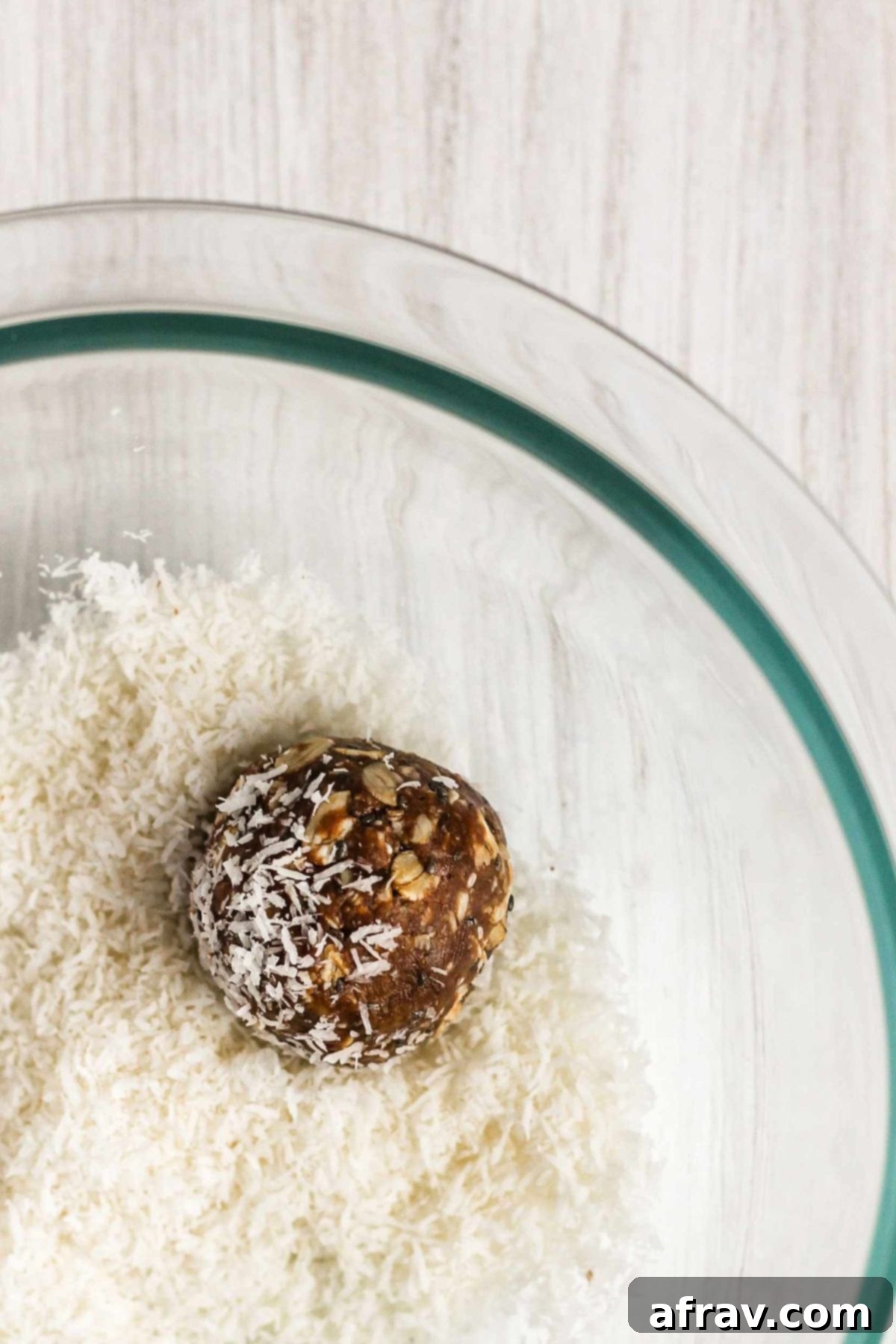Chocolate Coconut Peanut Butter Balls 7 Single peanut butter chocolate energy ball being rolled in a bowl of coconut flakes.