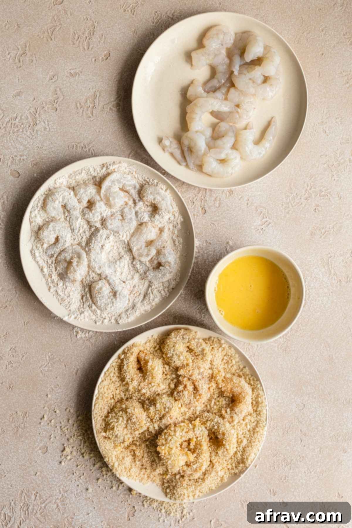 The process of breading the shrimp by coating in flour, egg and panko crumbs.
