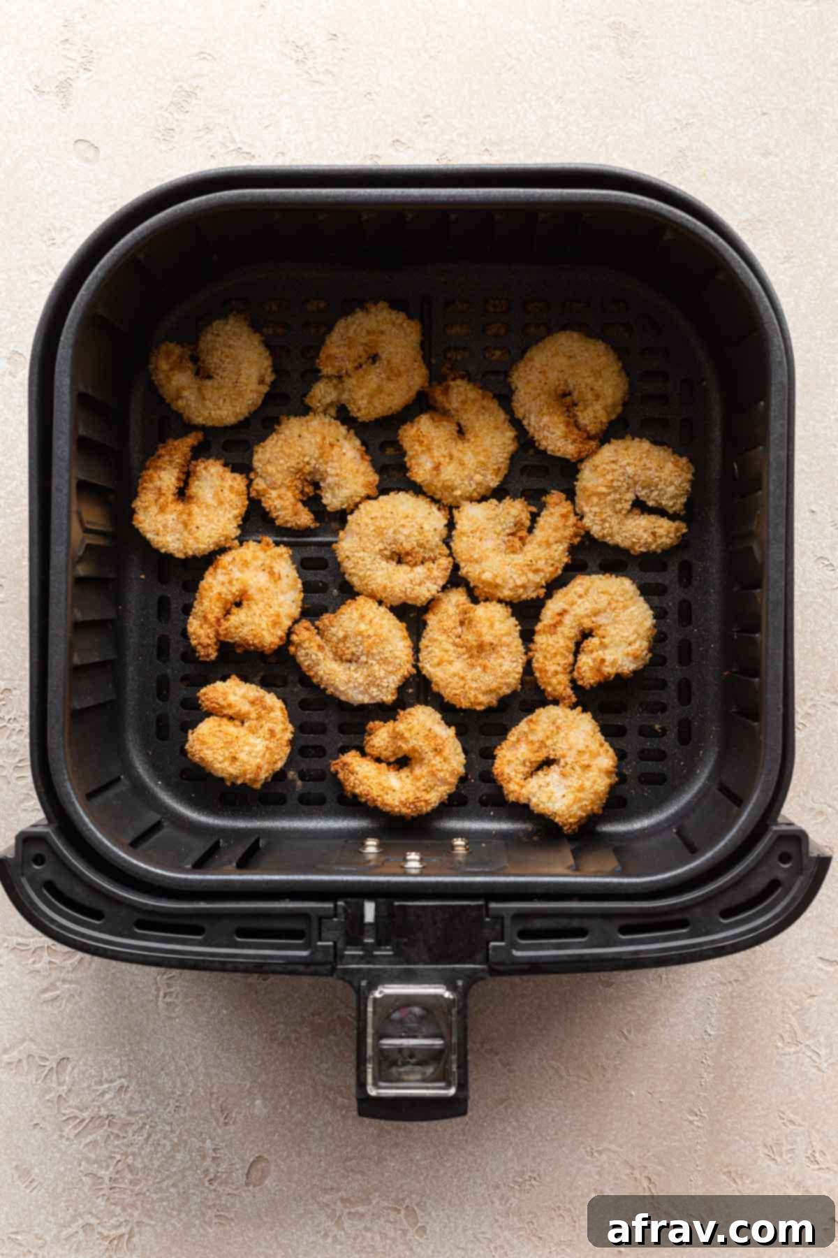 Overhead view of air fried breaded shrimp in an air fryer basket.