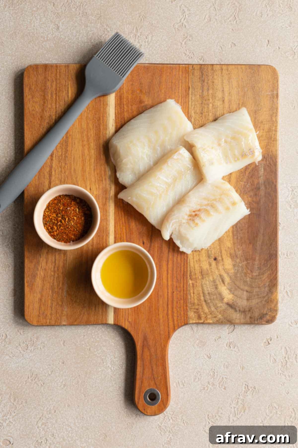 Crispy Air Fryer Fish Tacos 3 Cajun seasoning, oil and raw fish fillet pieces on a wooden cutting board.