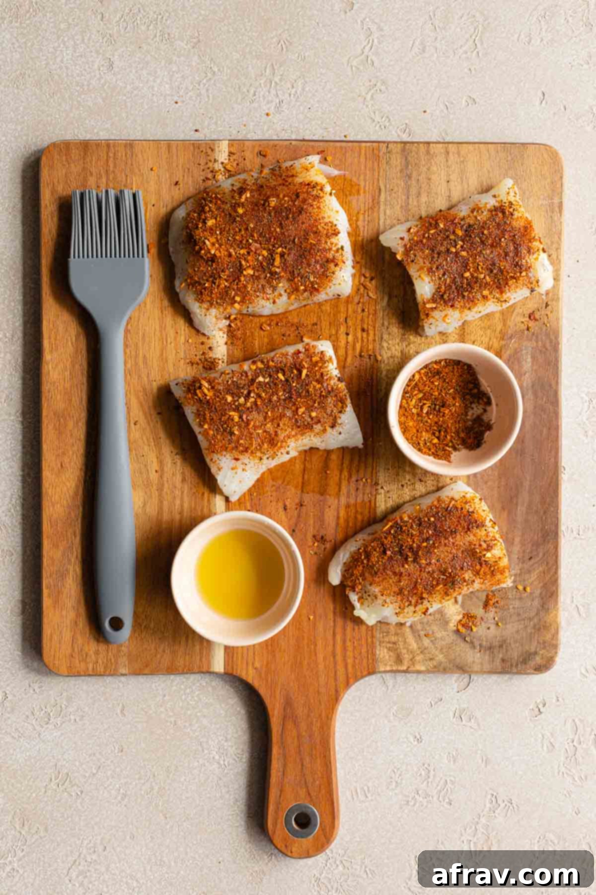 Crispy Air Fryer Fish Tacos 4 Raw fish fillet pieces arranged on a cutting board and coated in Cajun seasoning.