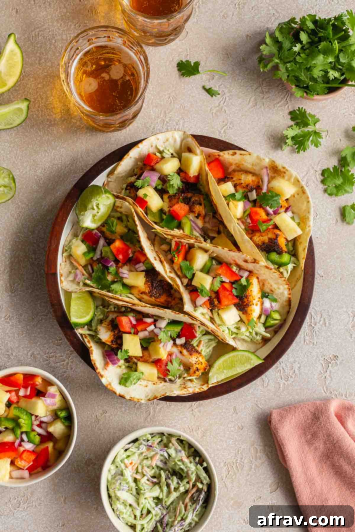 Crispy Air Fryer Fish Tacos 7 Overhead of fish tacos on a round plate with beer, slaw, cilantro and salsa off to the sides.