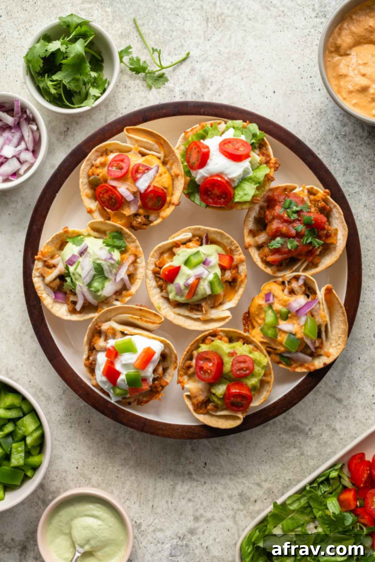 Overhead view of ground turkey taco cups arranged on a round plate with various toppings surrounding it, showcasing their vibrant appeal.
