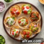 Overhead view of taco cups arranged on a round plate with a variety of toppings.