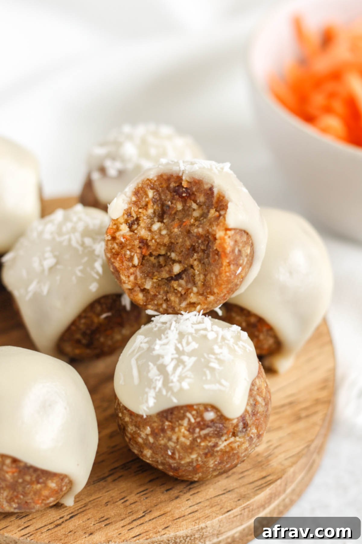 Carrot cake ball topped with glaze bit in half to show texture, showing a moist, textured interior with visible carrot and nuts.