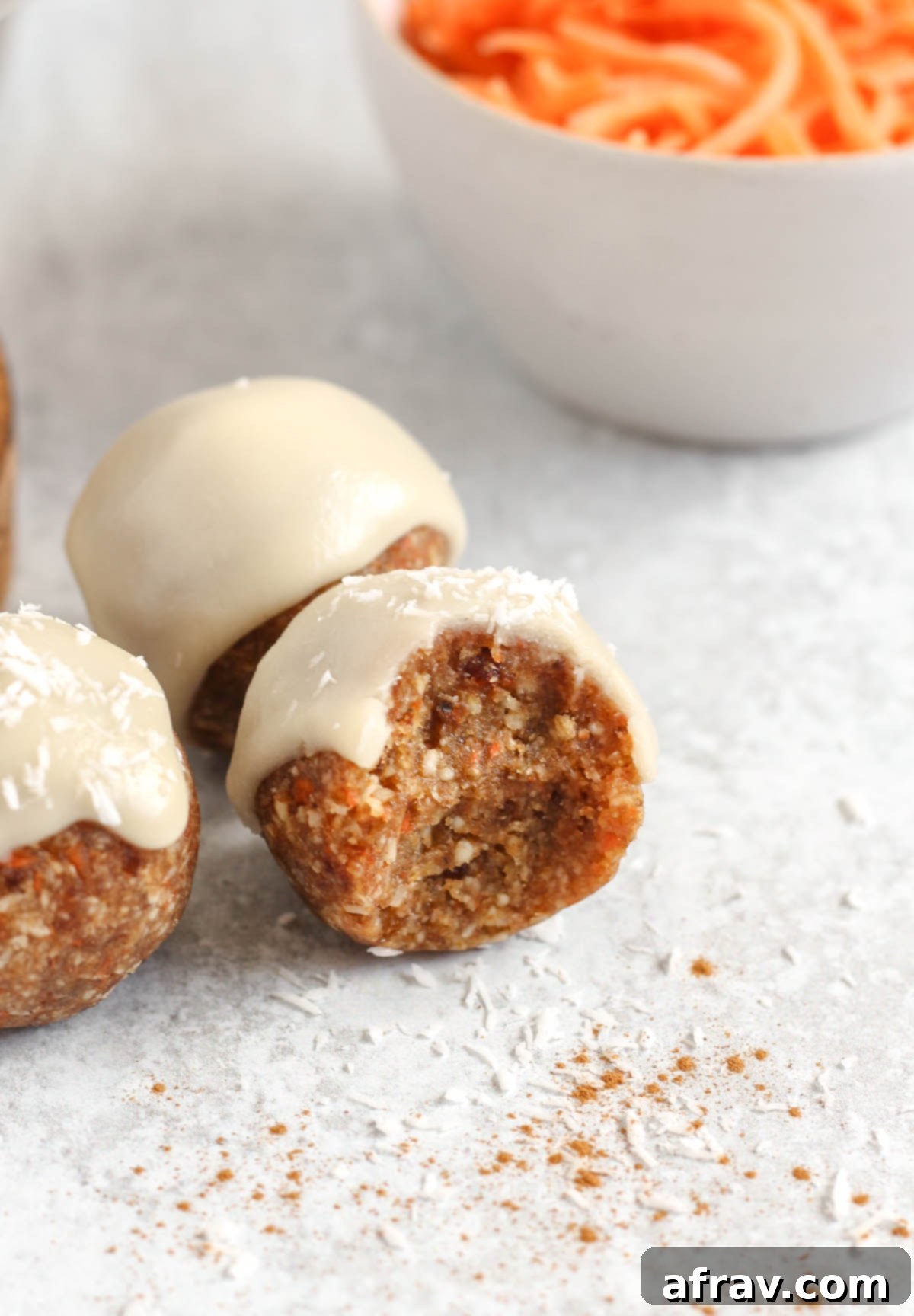 A carrot cake ball with a bit taken out to show texture with 2 balls behind.
