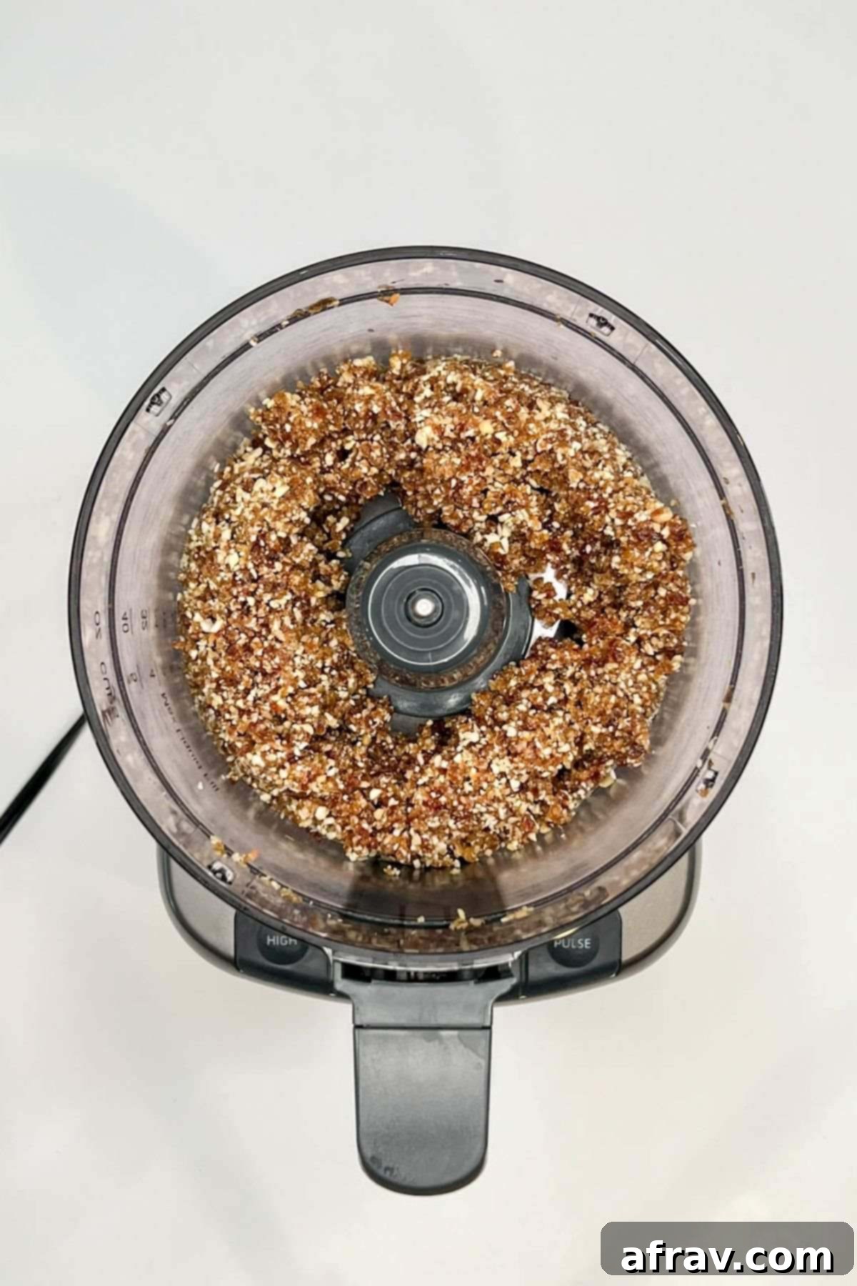 Blended dates and nuts in a food processor, forming a coarse paste.