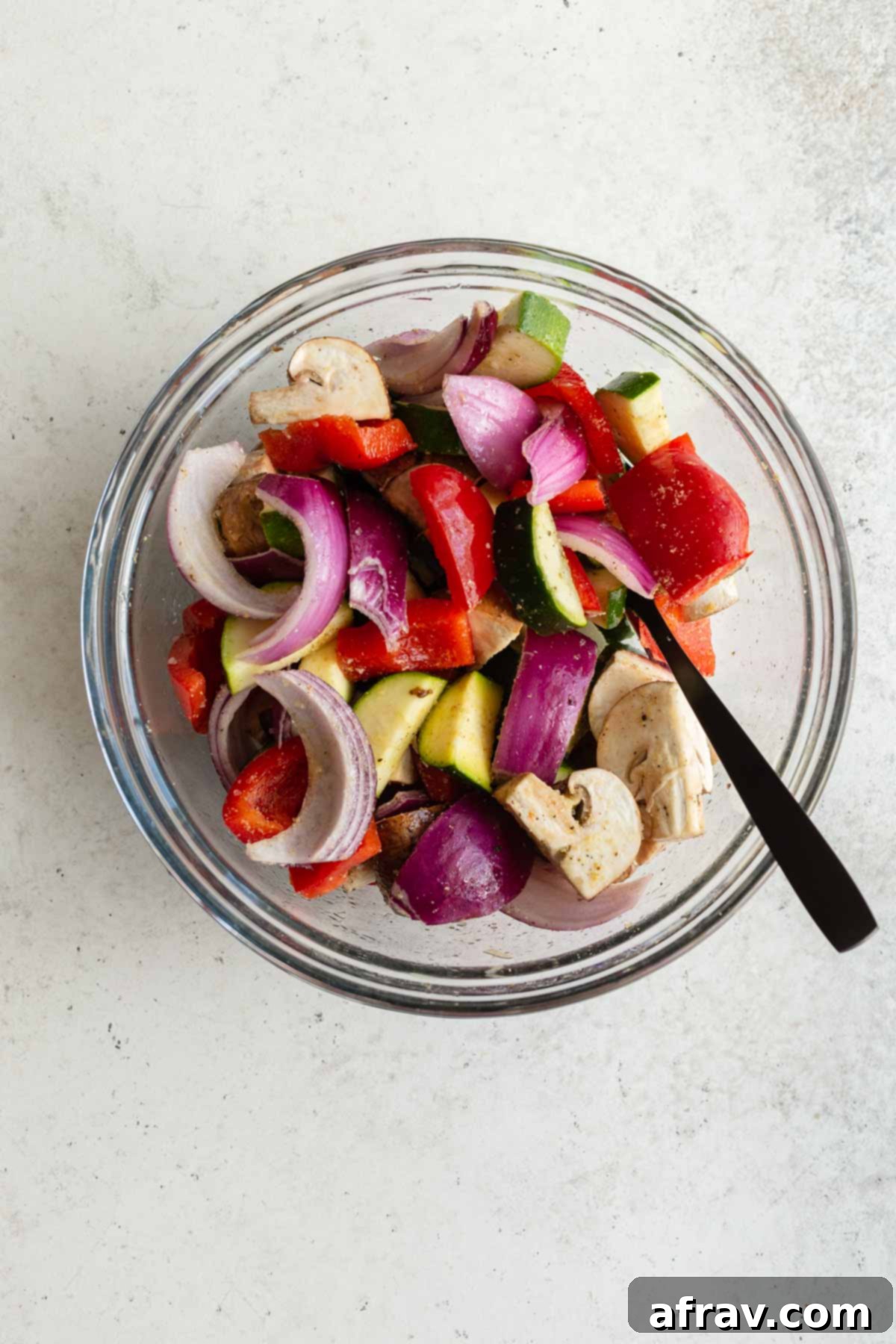 Crispy Air Fryer Veggies 4 Chopped and seasoned vegetables in a glass bowl with a spoon.