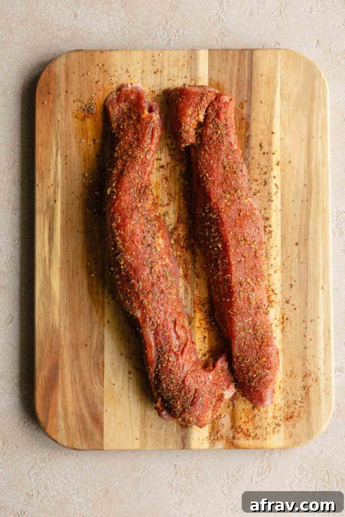 Perfect Air Fryer Pork Tenderloin 5 Seasoned pork tenderloins coated with a savory rub on a wooden board, ready for the air fryer.