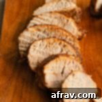 Perfect Air Fryer Pork Tenderloin 10 Close up side view of slices of pork tenderloin on a wooden board, ready to serve.