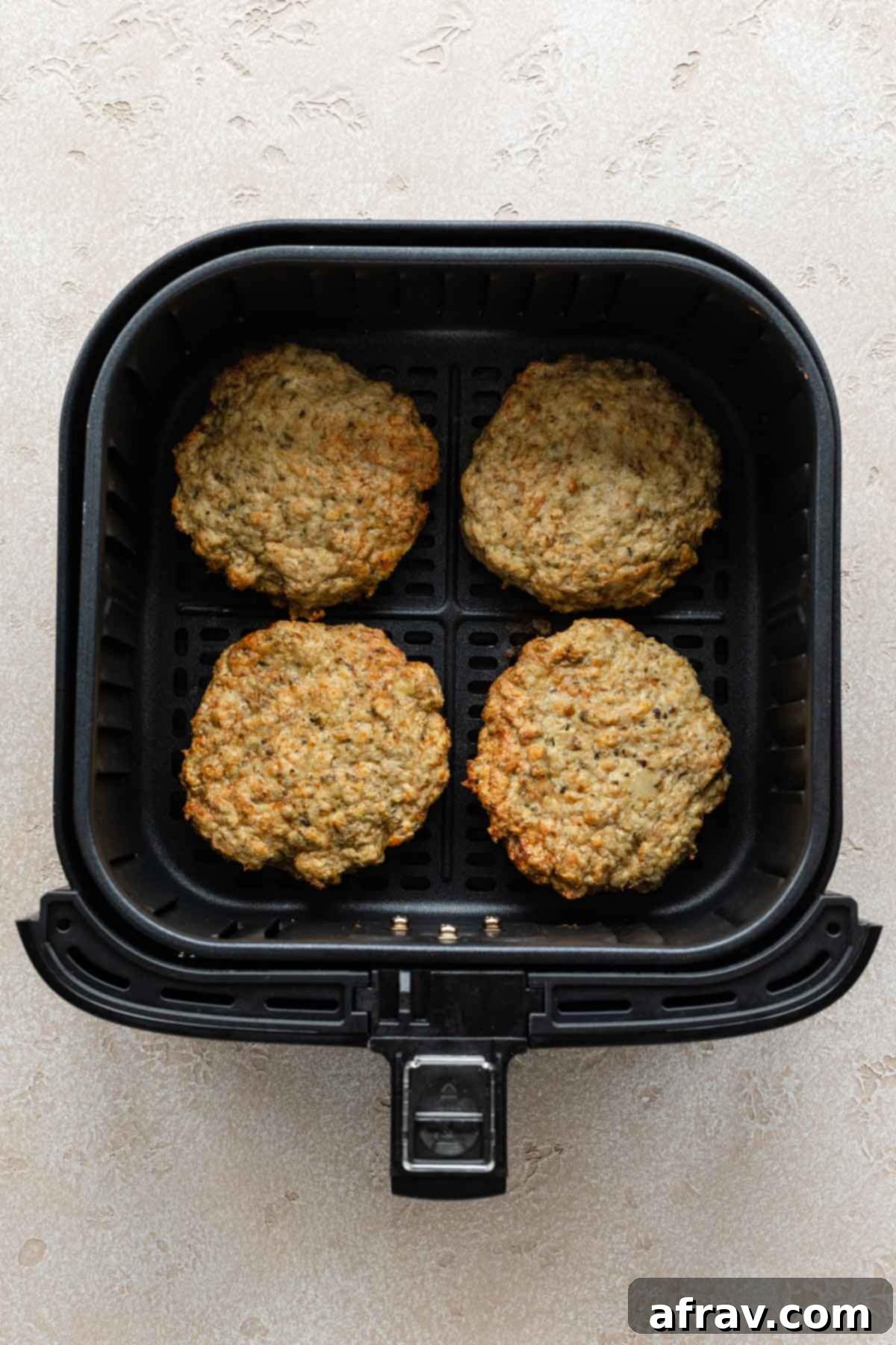Four turkey burgers cooked in an air fryer basket.