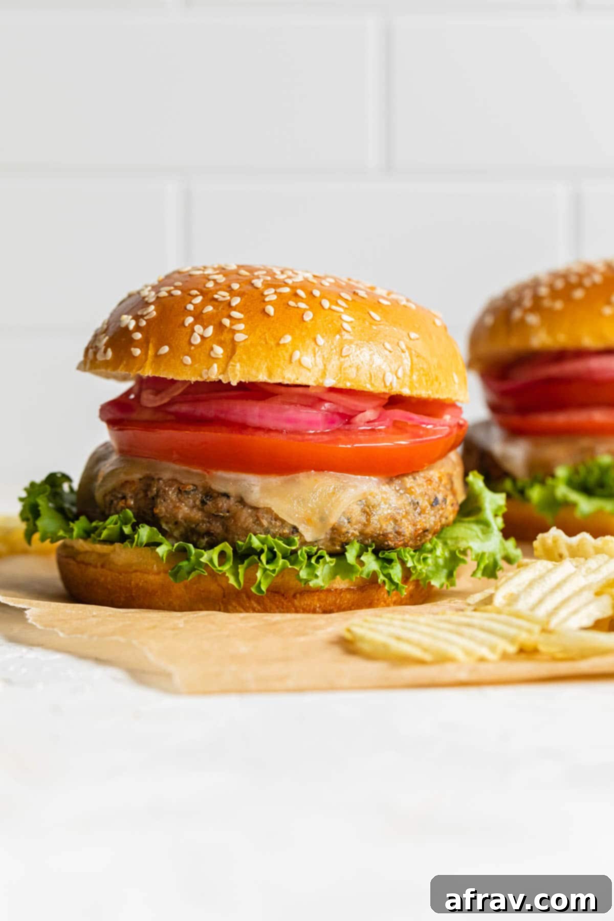 Up close side view of a turkey burger on a sheet of brown parchment paper.