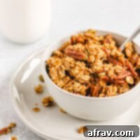 Wholesome Pumpkin Crunch Granola Gluten Free Plant Based 8 A bowl of homemade pumpkin granola on a small plate with a glass jar of milk behind it, perfect for a cozy fall breakfast.