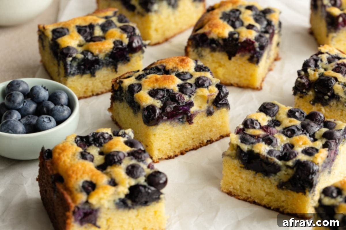 Squares of blueberry cake neatly arranged on a sheet of parchment paper, highlighting the tender crumb.