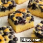 Blueberry cake cut into squares and arranged on parchment paper, ready to serve.