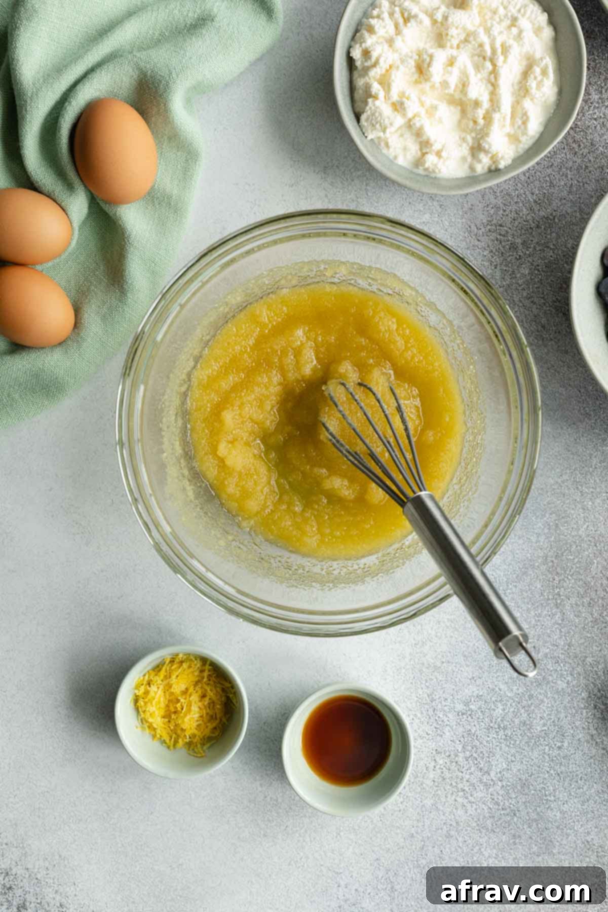 Sugar and oil being whisked together in a glass bowl, illustrating the first step.