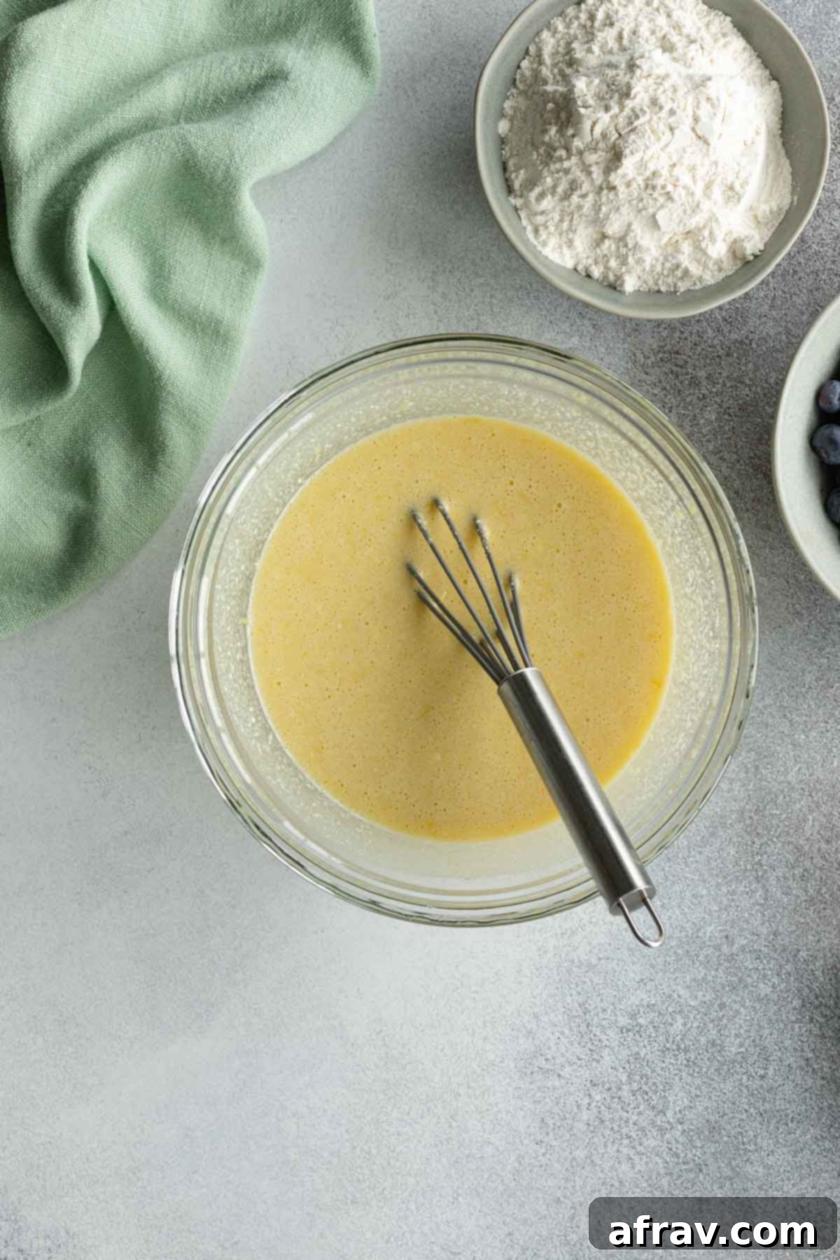 Ricotta, lemon zest, and vanilla whisked into the egg, sugar, and oil mixture in a glass bowl.