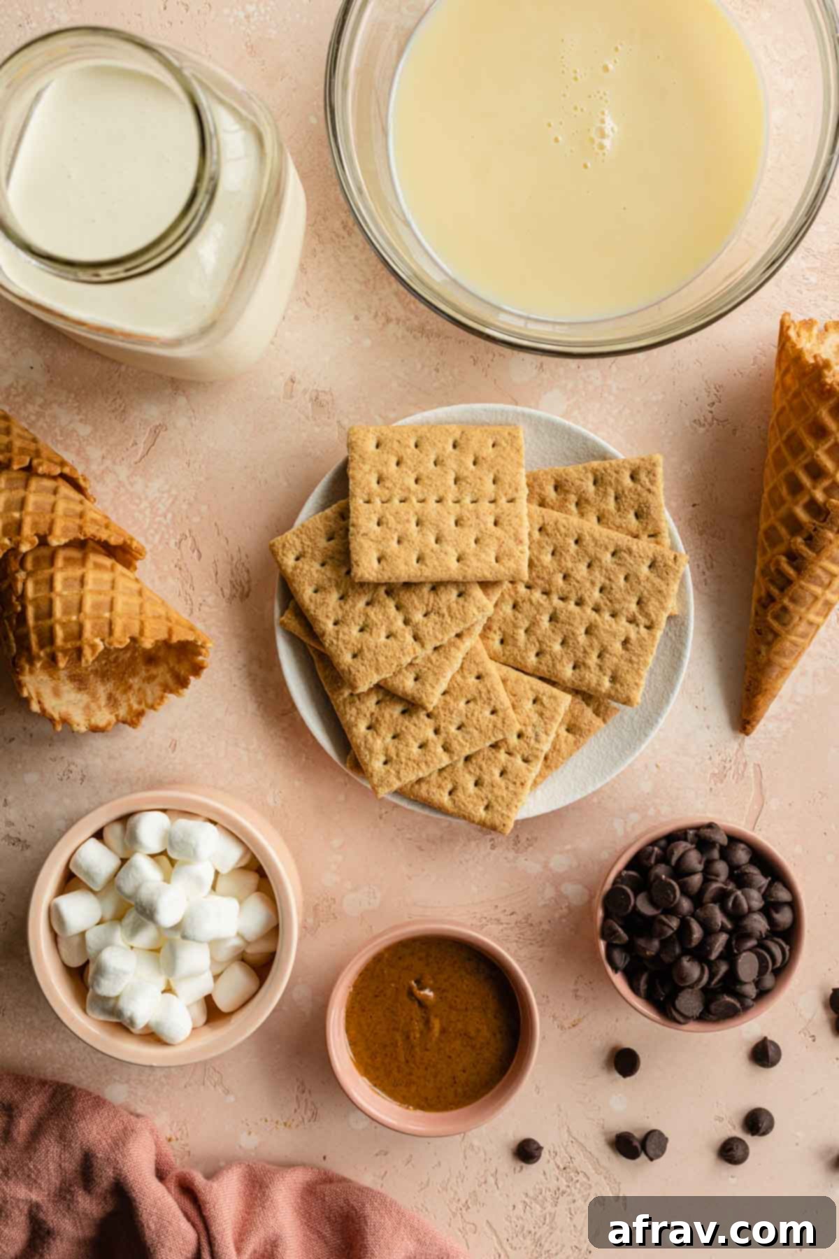 Ingredients to make s'mores ice cream arranged individually on a pink surface.