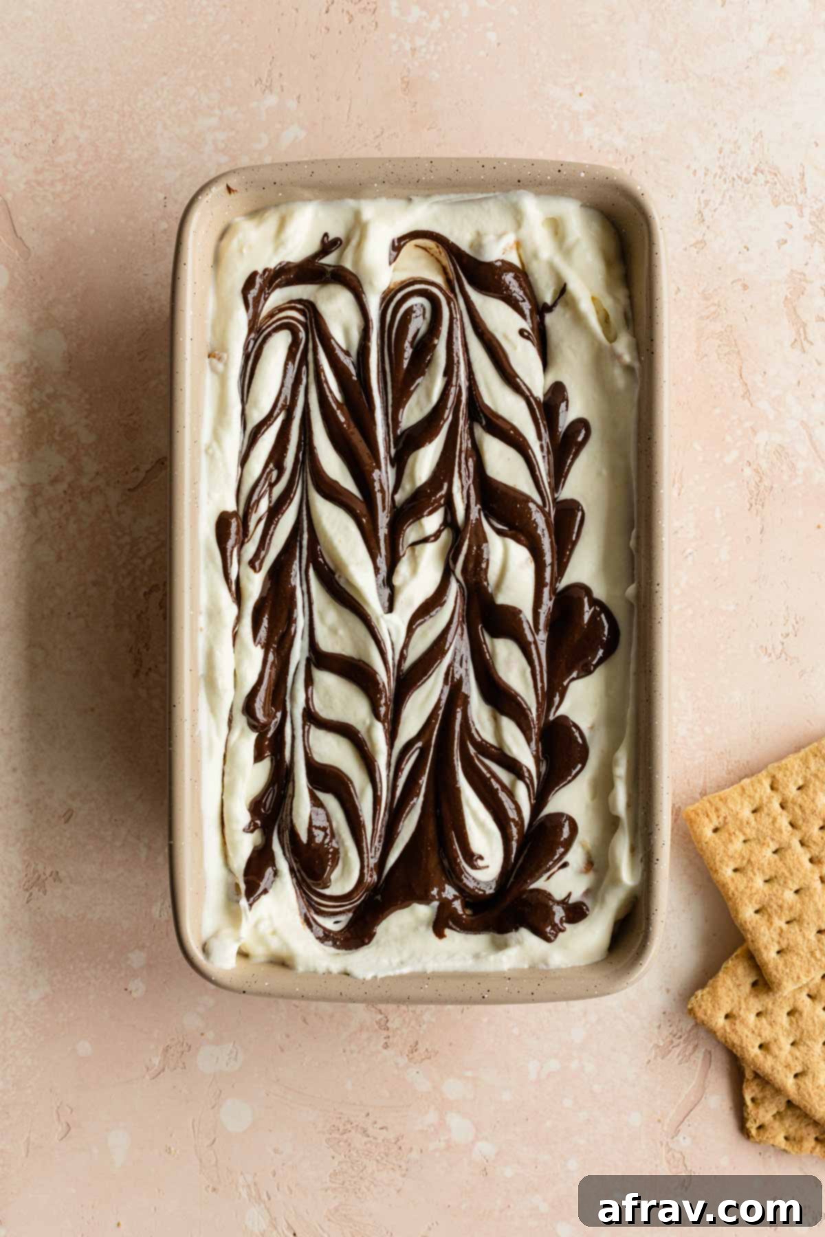 Ice cream mixture in a loaf pan with melted chocolate swirled around on the top.