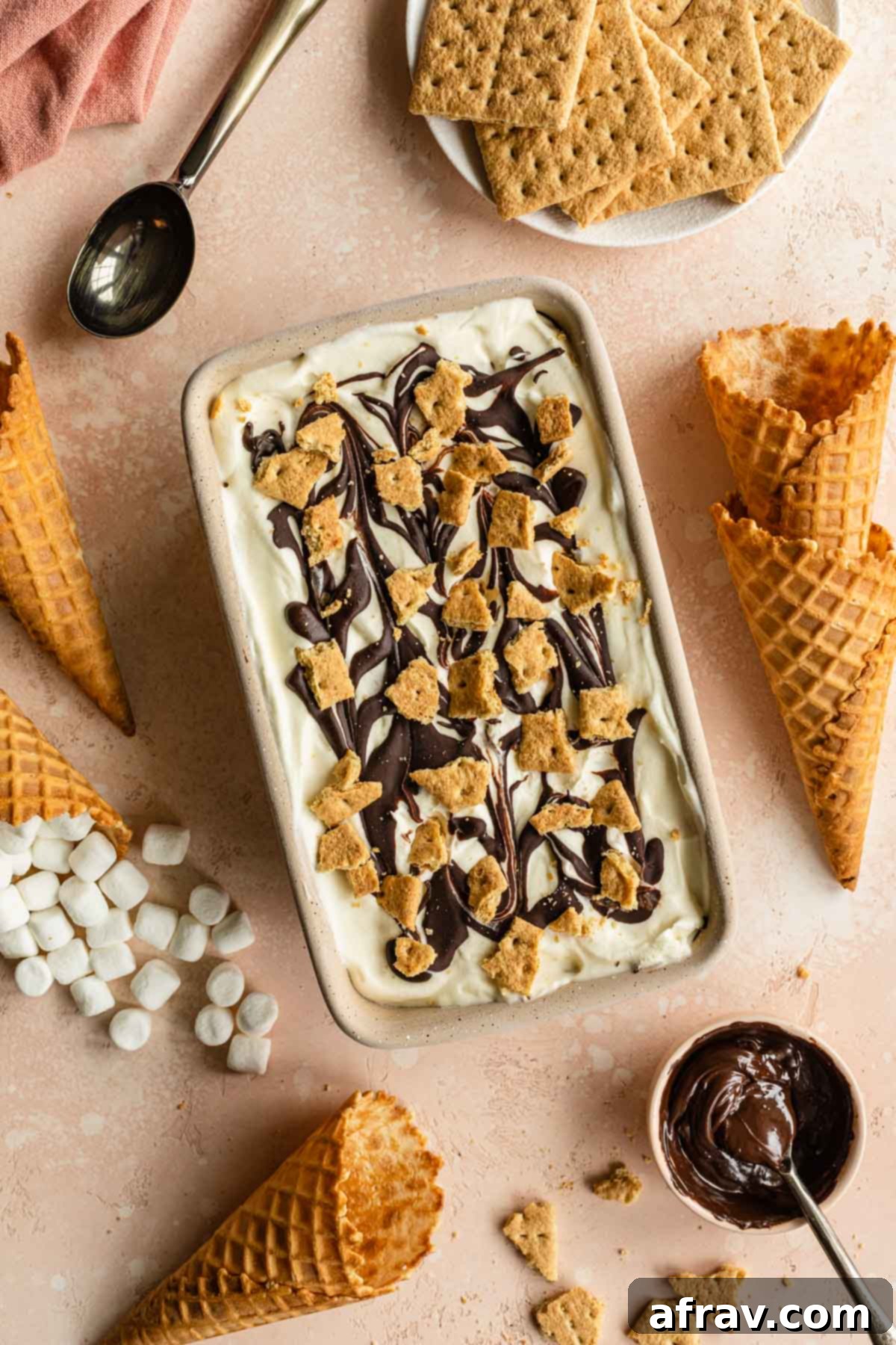 S'mores ice cream in a loaf pan and surrounded by marshmallows and waffle cones.