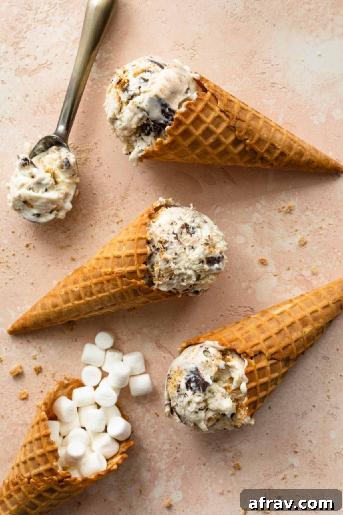 S'mores ice cream in waffle cones and arranged on a pink surface.