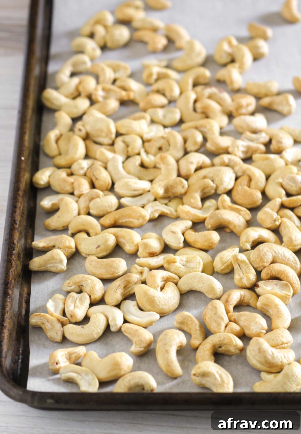Raw cashews on a vintage baking sheet lined with parchment paper.