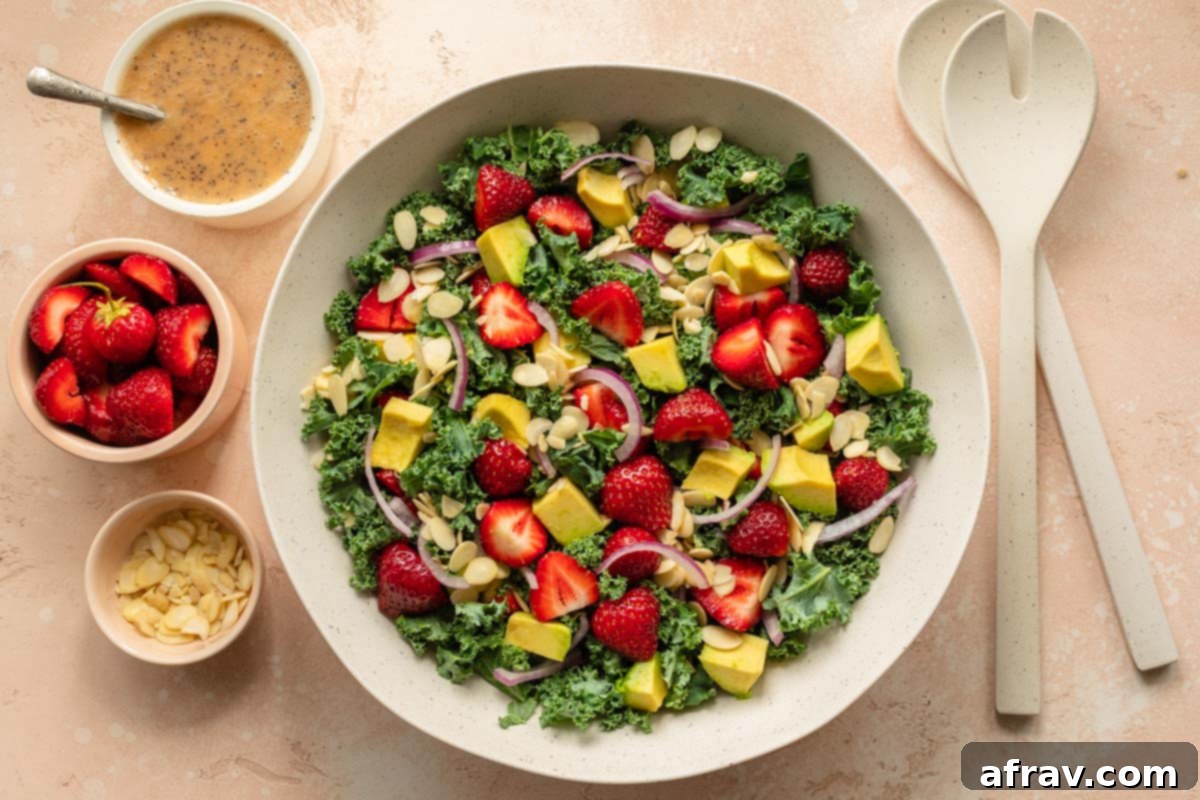 Vibrant Strawberry Kale Salad 7 Strawberry avocado kale salad in a large white bowl with poppyseed dressing on the side, ready to be served.