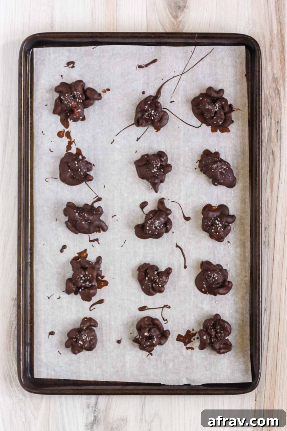 Chocolate cashew clusters on a baking sheet lined with parchment paper.