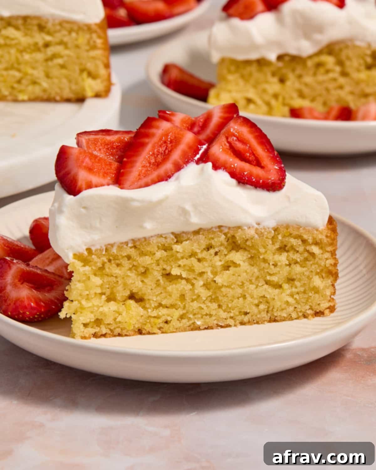 Side view of a slice of cake on a plate topped with whipped cream and strawberries.