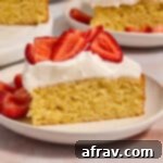 Slice of almond flour lemon cake on a plate and topped with whipped cream and strawberries.