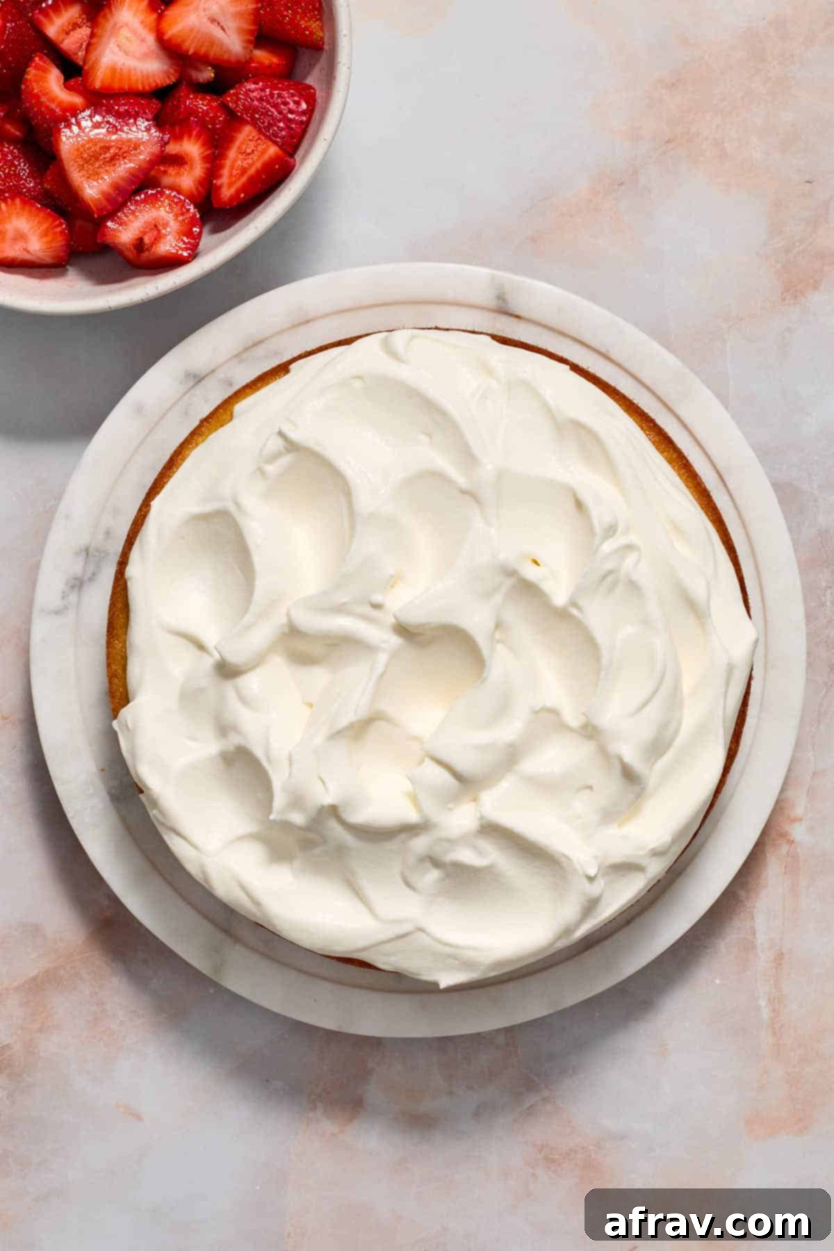 Cake topped with whipped cream with strawberries on the side.