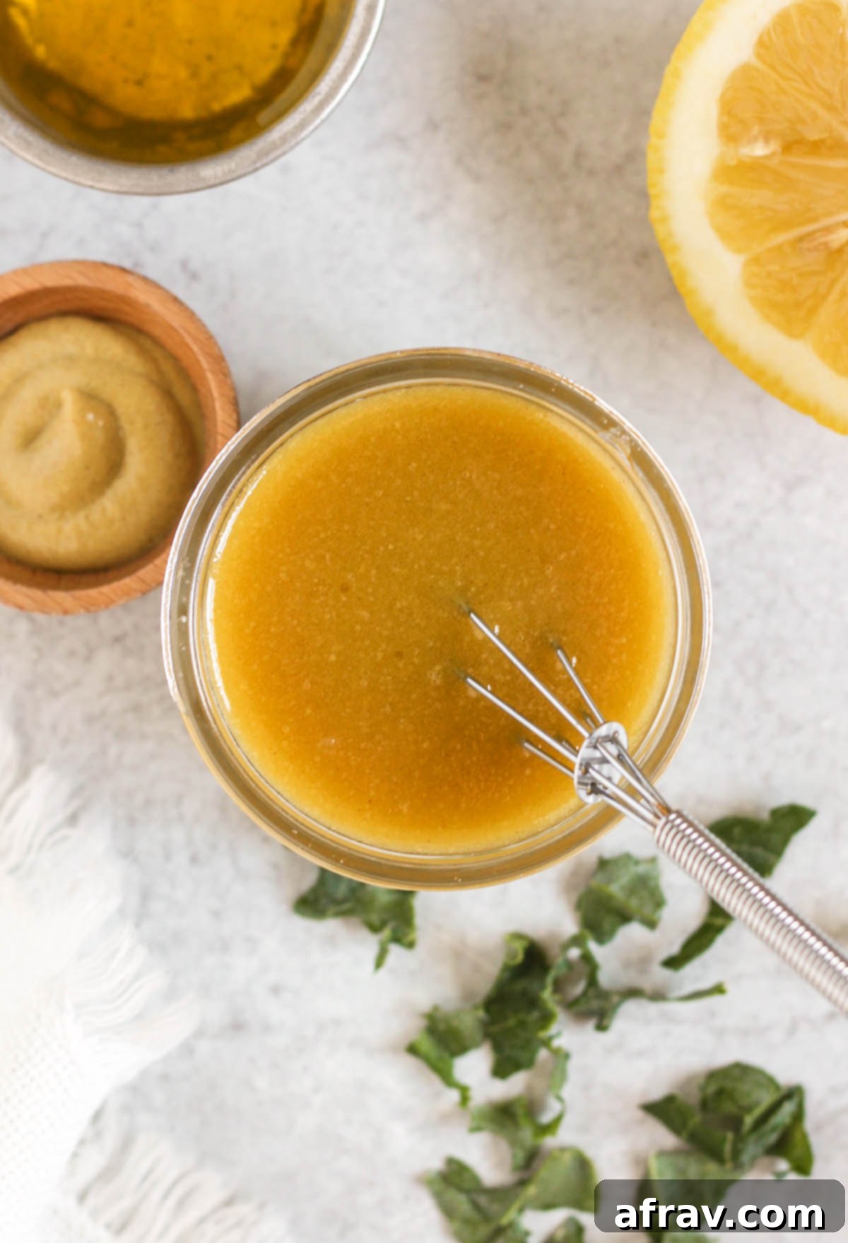 Overhead view of maple Dijon dressing in a small mason jar with a small whisk in the jar.