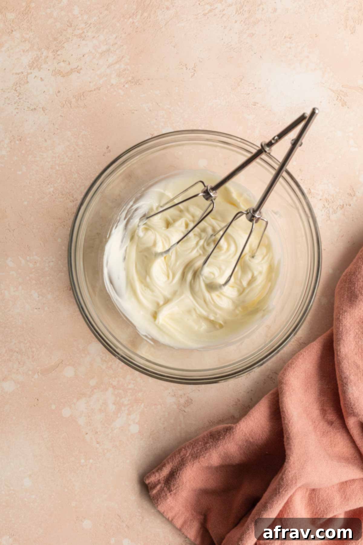 Creamy, smooth cream cheese frosting in a glass bowl, ready to be spread.